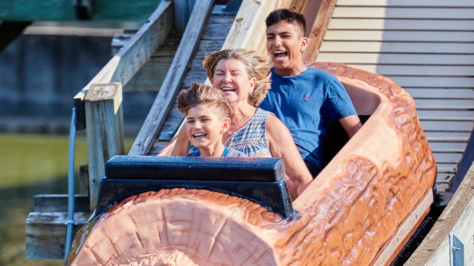 Log Flume boat racing down the hill with three riders' faces distorted by the wind